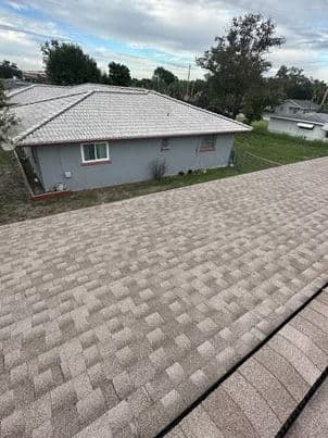 Roofing shingles on a residential home with a cloudy sky in the background.