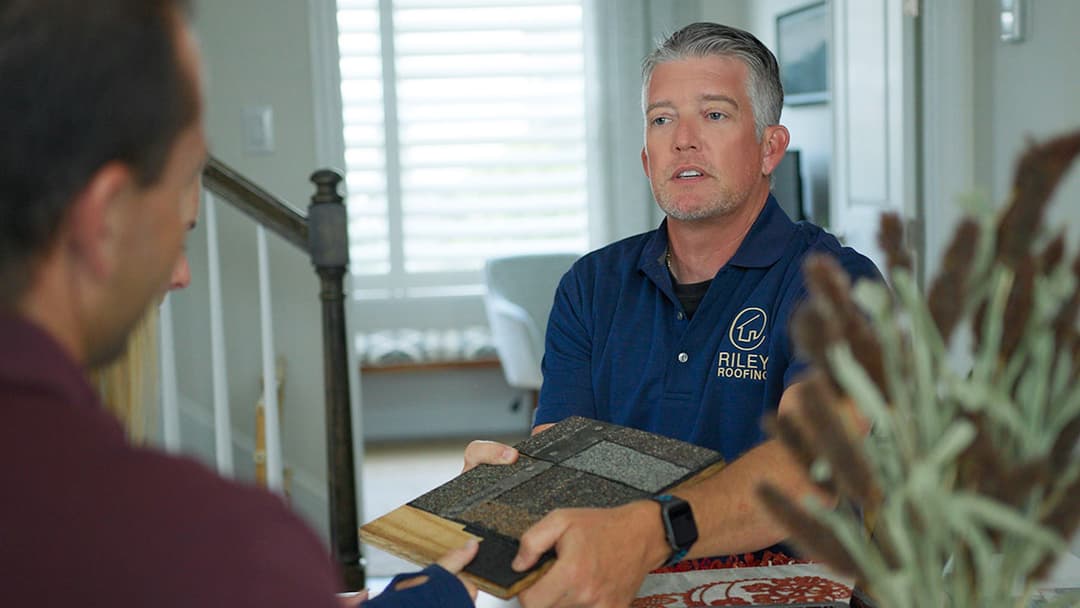 Riley Roofing expert showcasing roofing material samples during a consultation.